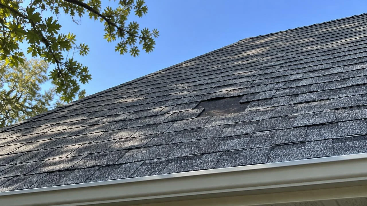 Bare patch on a shingle roof where three shingles are missing.