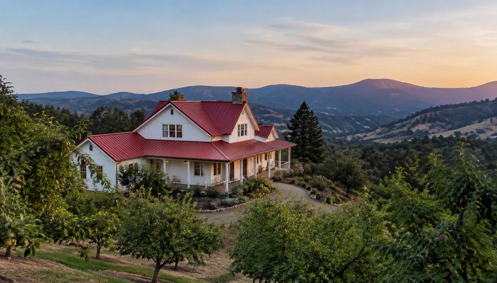 White farmhouse with a red metal roof above an orchard on a hillside.
